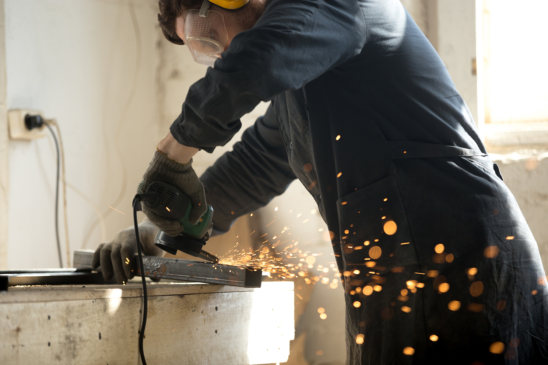 skilled workman grinding metal profile pipe with lot of sparks